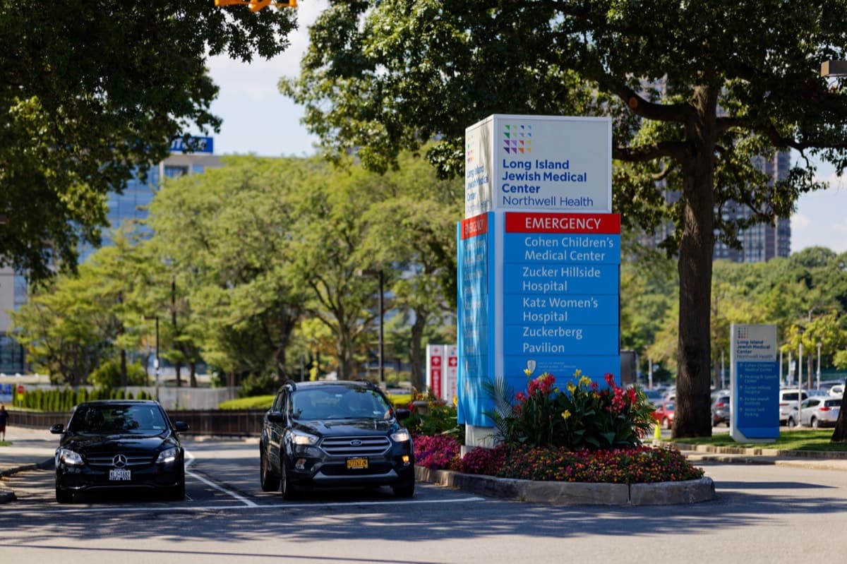 The tree-lined driveway entrance and signpost of Long Island Jewish Medical Center.