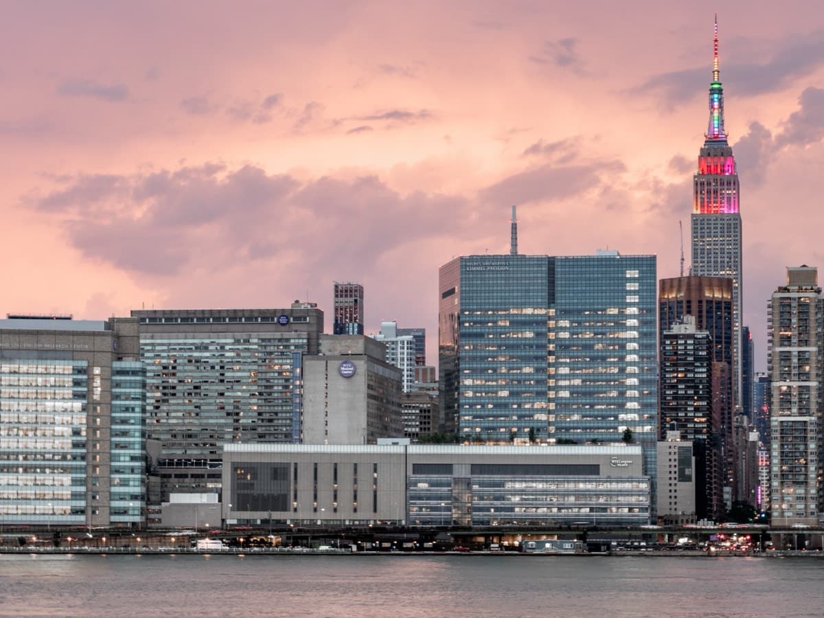 NYU Langone's medical campus on the East River waterfront at dusk, with the Empire State Building behind.